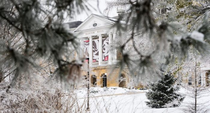Rime ice coats the branches of trees flanking Bascom Hall on snow-covered Bascom Hill at the University of Wisconsin-Madison during a foggy winter day on Jan. 6, 2021. In between the building’s columns hangs a three panel graphic of UW-Madison mascot Bucky Badger. Unlike hoarfrost – which typical forms on clear, cold nights – rime ice forms when moisture in the foggy air coats nearby surfaces and freezes. (Photo by Jeff Miller / UW-Madison)