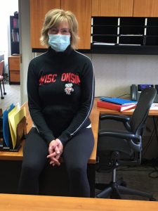 Peggy Ziebarth at her desk in Bascom Hall wearing a face covering.