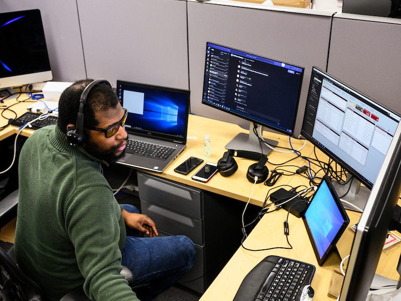 Considered essential personnel during COVID-19, Department of Information Technology (DoIT) employees Alex Robinson (foreground) and Ben Pomerening provide technical support for desktop computers while working in Rust-Schreiner Hall at the University of Wisconsin-Madison on 15 April 2020, most of the UW-Madison campus is closed in response to the rapidly evolving health concerns of the global coronavirus (COVID-19) pandemic. (Photo by Jeff Miller/UW-Madison)