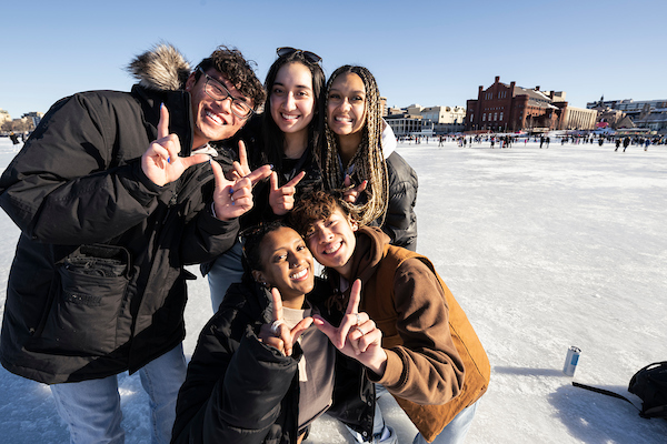 Clockwise from upper left, UW–Madison undergraduate students Andre Sarichith, Alyah Garcia, Mya Brown, Aaron Dong, and Saron Fenta throw W hand signs and pose for a photo on frozen and ice-covered Lake Mendota during the Wisconsin Union’s Winter Carnival along the University of Wisconsin–Madison shoreline near the Memorial Union Terrace on Feb. 11, 2023. (Photo by Jeff Miller / UW–Madison)